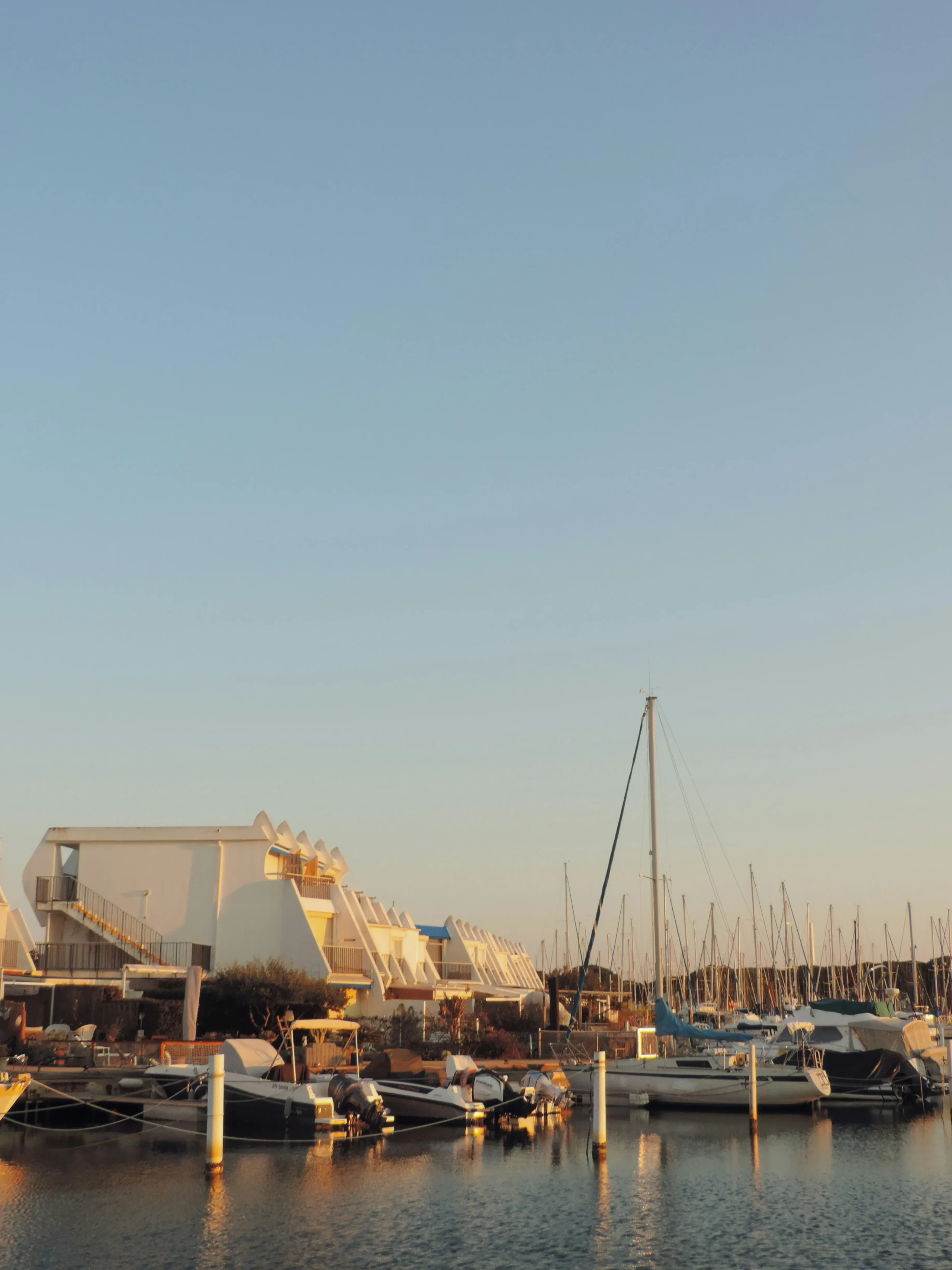 Marina avec bateaux et bâtiments modernes au coucher du soleil, Hôtels Aigues-Mortes Camargue - Les Jardins du Canal